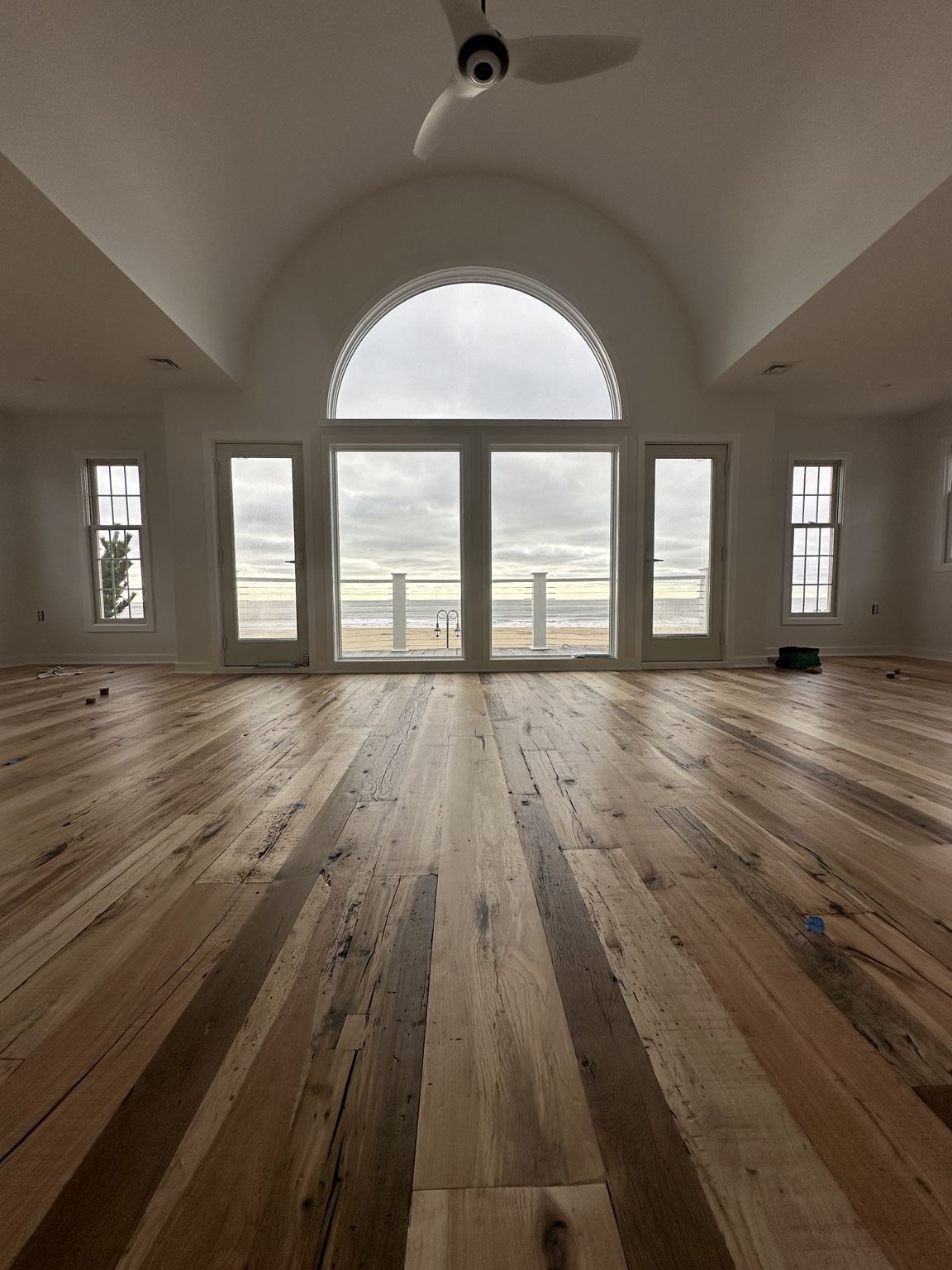 Varied-tone plank floor in a large room with arched windows