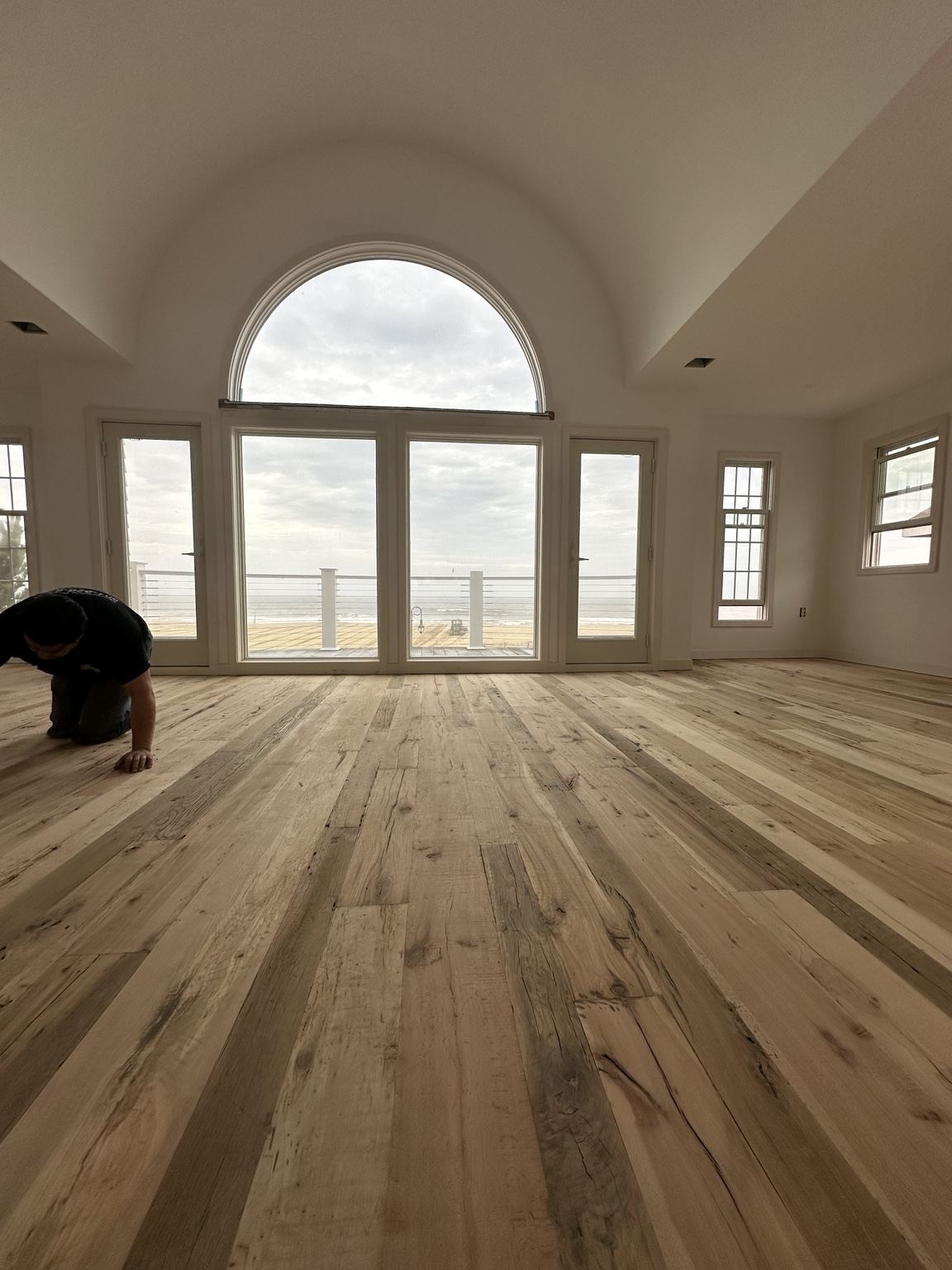Varied-tone plank floor in a room with arched windows, photographed during on-site work