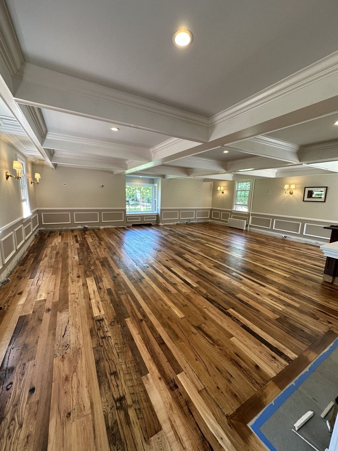 Varied-tone plank floor in a paneled room, photographed during on-site work
