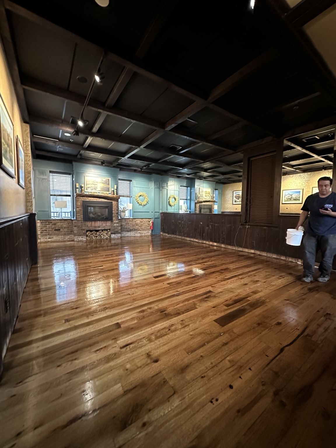 Varied-tone wood floor in a dark-paneled room, photographed during on-site work