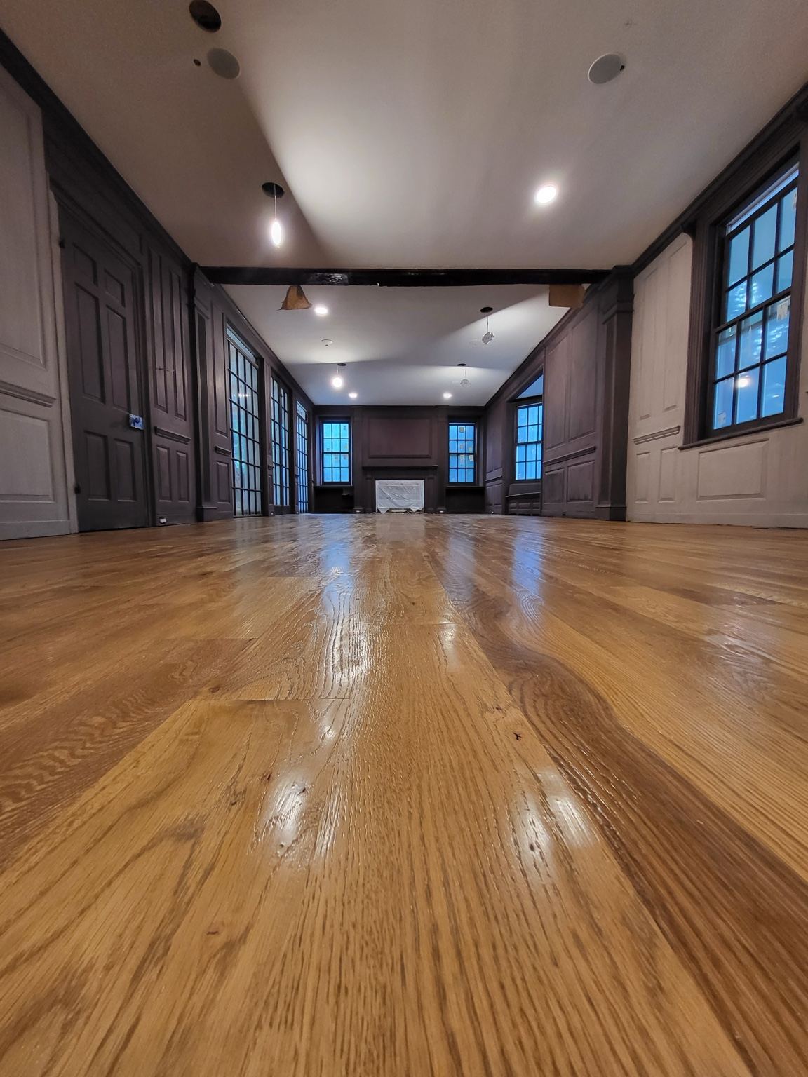 Low-angle view across a glossy wood floor in a paneled room