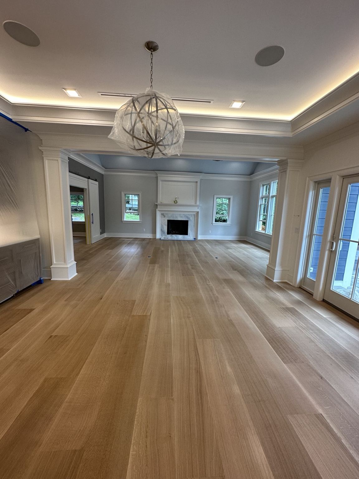 Light plank wood floor in a room with a fireplace and orb chandelier
