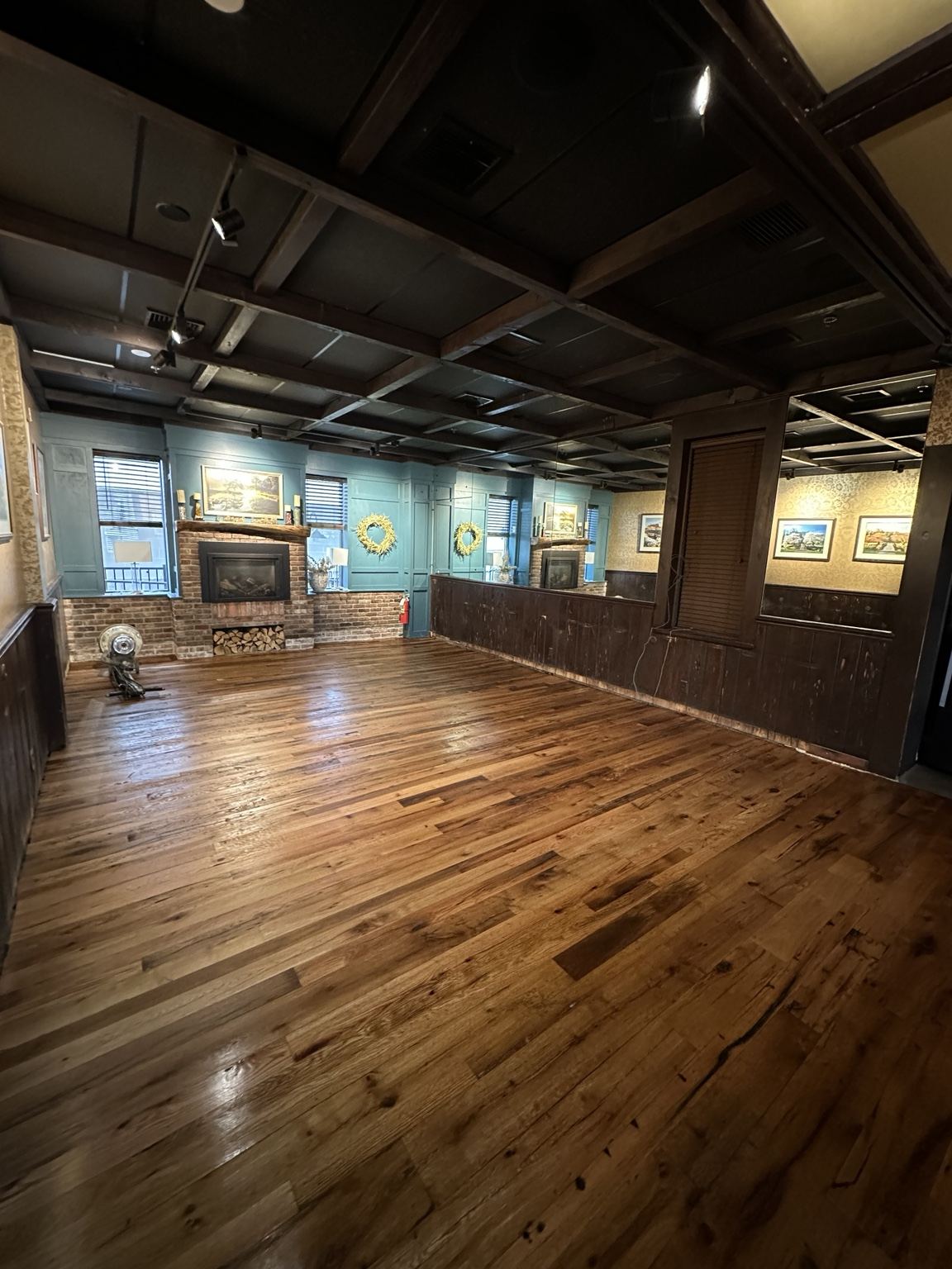 Varied-tone wood floor in a dark-paneled interior with fireplace