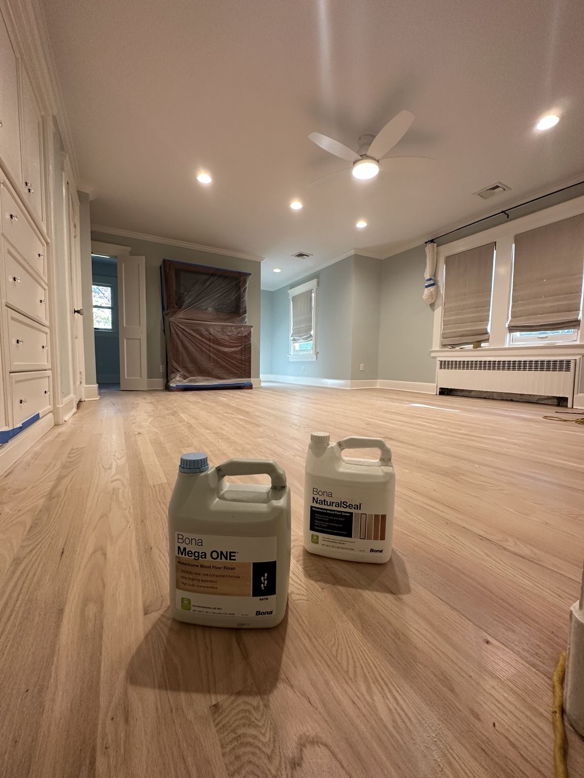 Professional floor-finish containers staged on a light wood floor