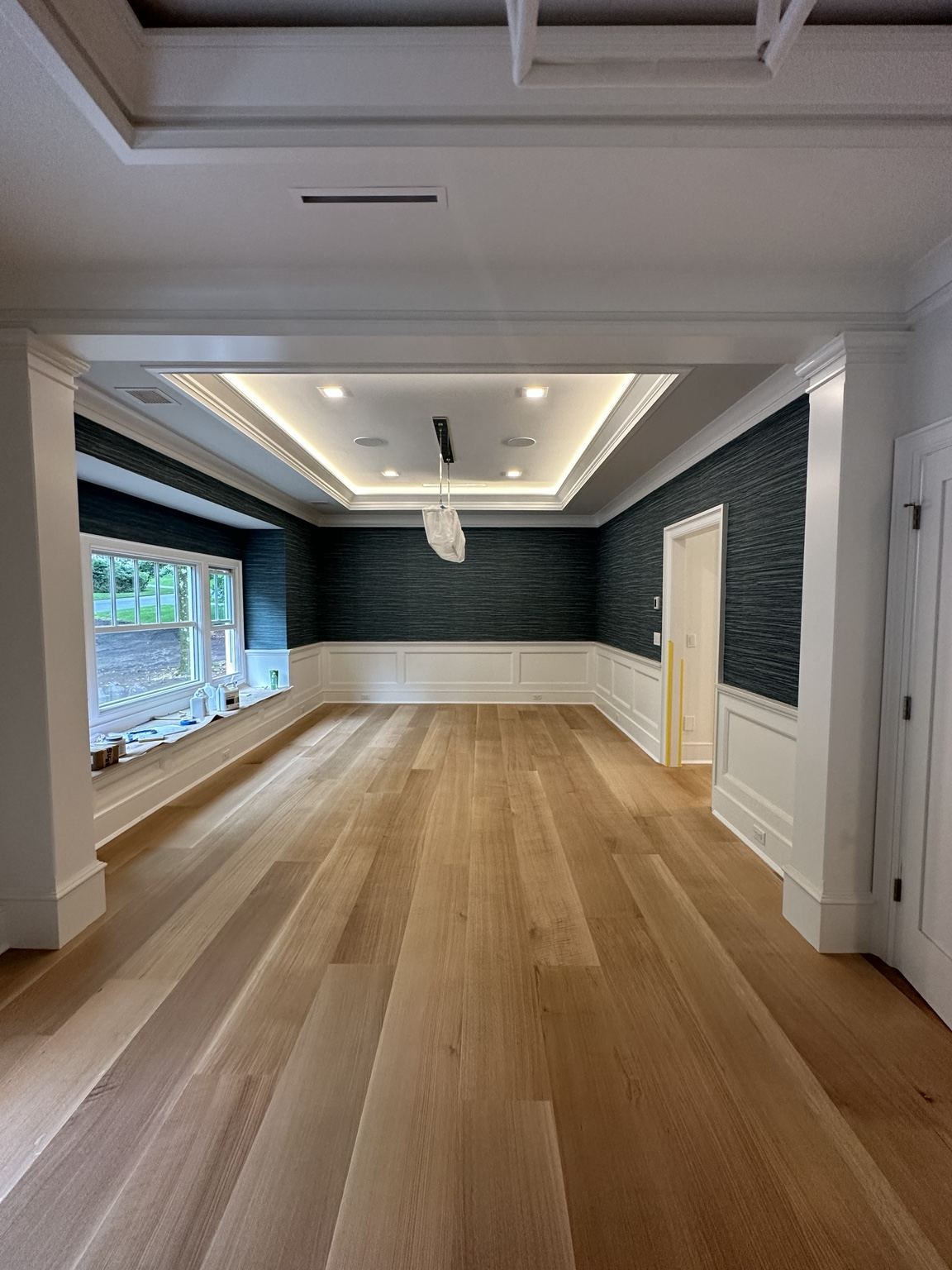 Wide-plank wood floor in a room with coffered ceiling and wainscoting