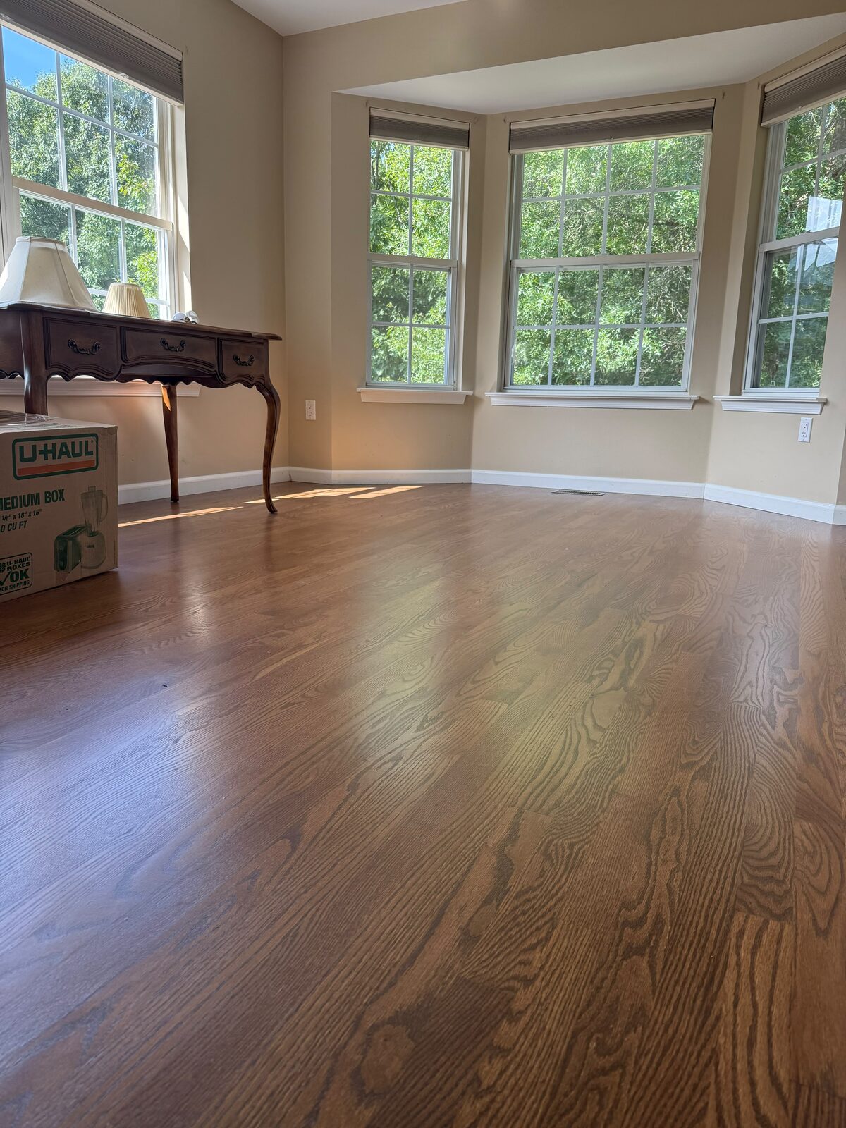 Finished stained hardwood floor in a sunlit room with bay windows