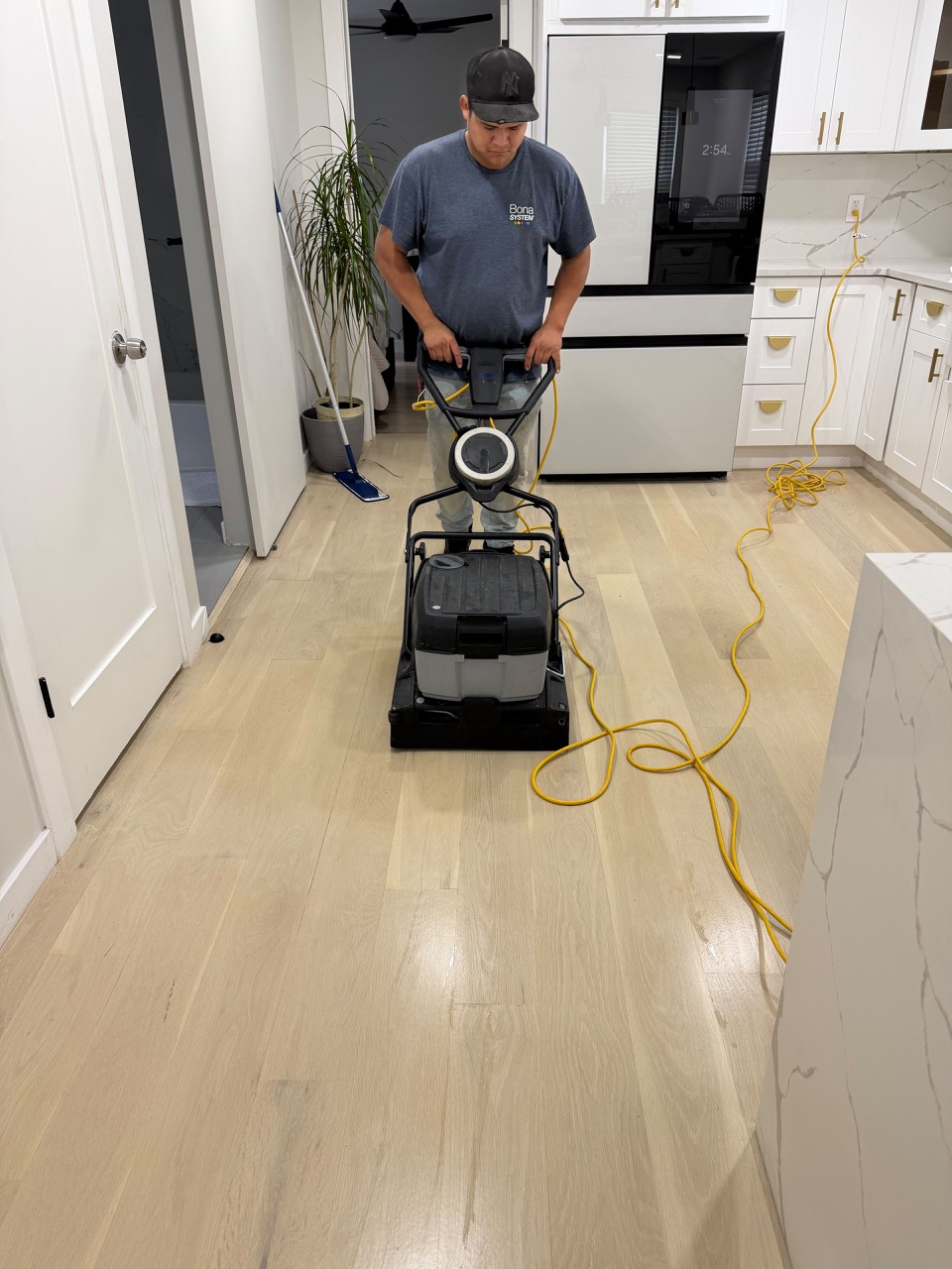 HQ technician cleaning a hardwood kitchen floor with Bona PowerScrubber in Roselle Park, NJ.